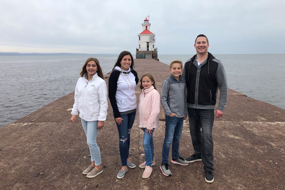 Chris Kellett with his family in front of a lighthouse